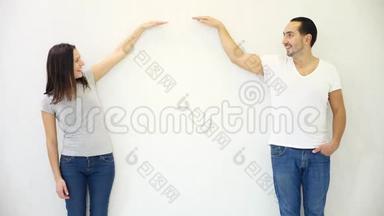 Brunette的男人和女人站在白色的墙壁背景下，放下手，表现出失落和失落